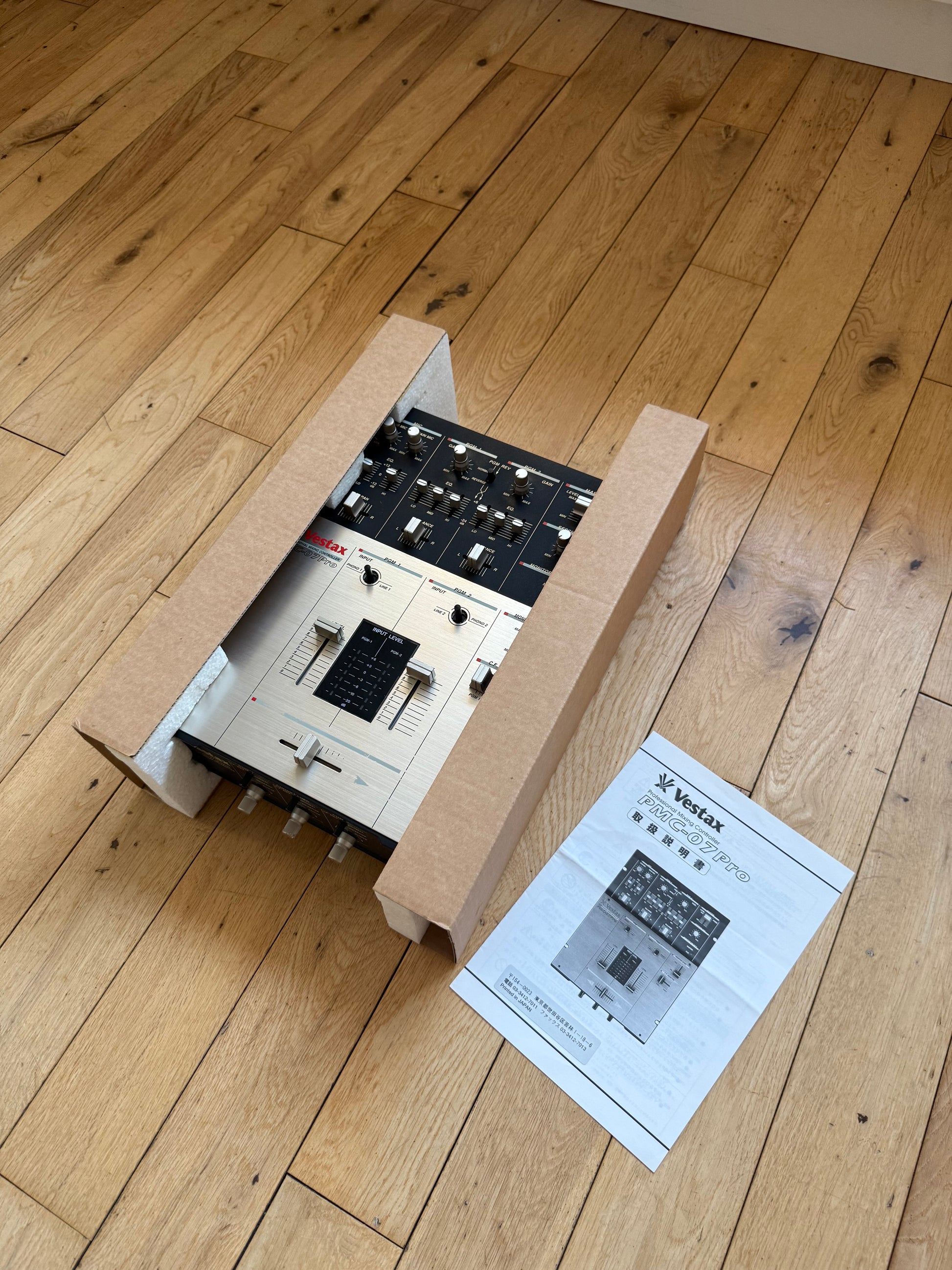 Angled view of a serviced Vestax PMC-07 Pro with original Japanese instruction manual.